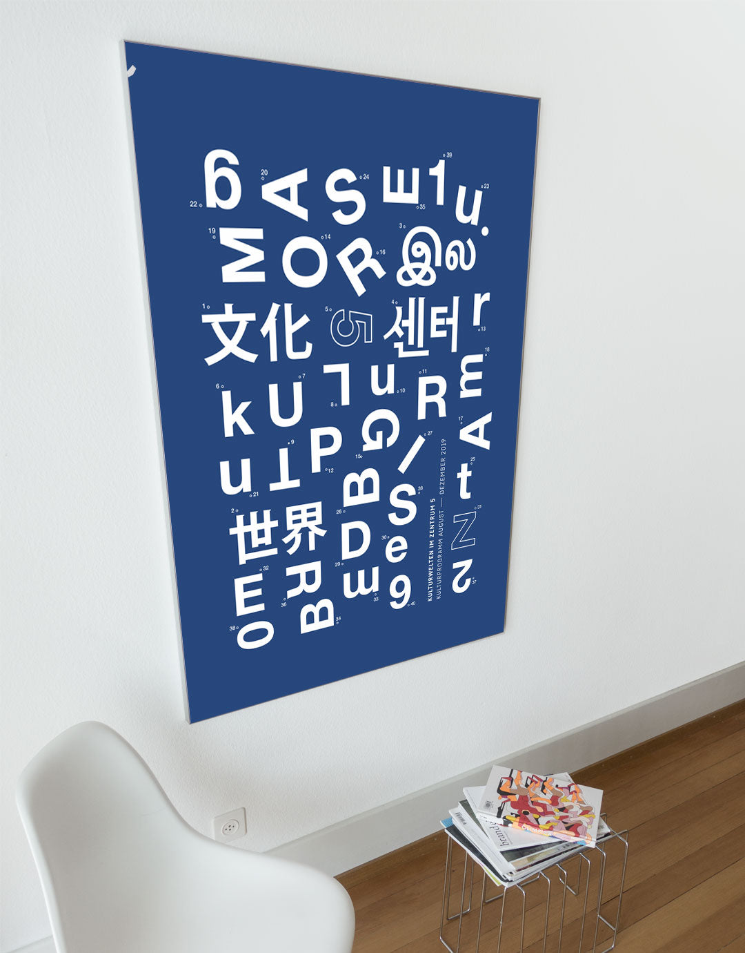 Poster mit einer kreativen Anordnung von Buchstaben und Zeichen in verschiedenen Sprachen auf einem blauen Hintergrund, das die Kulturwelten 2019 darstellt. Die Gestaltung kombiniert verschiedene Schriftarten und -stile, um ein modernes und dynamisches Kunstwerk zu schaffen, ideal für Liebhaber zeitgenössischer Grafiken und kultureller Themen.