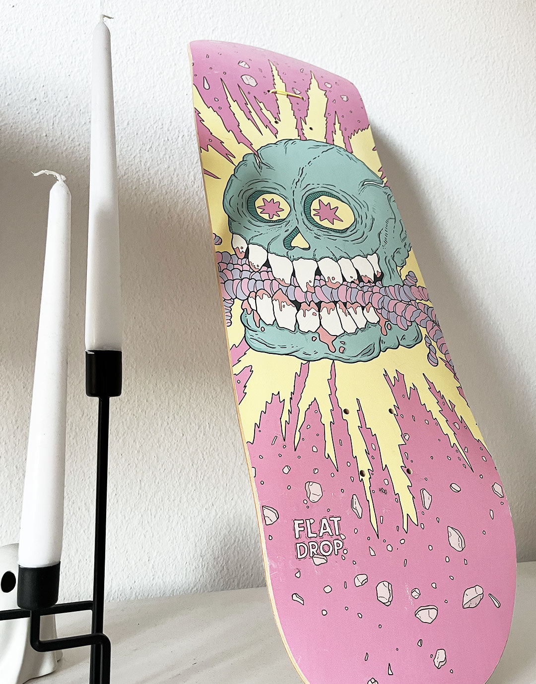 Skateboard-Deck mit einer kreativen Illustration von Würmern, welche von einem Schädel verschlingt werden, umgeben von lebendigen Farben und dynamischen Mustern. Inspiriert von urbaner Kunst und zeitgenössischem Design, ideal für Liebhaber von ausgefallenen und verspielten Motiven.