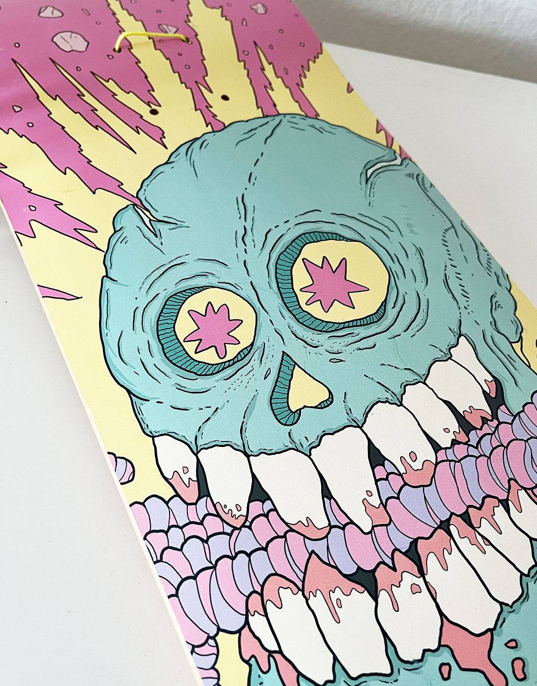 Skateboard-Deck mit einer kreativen Illustration von Würmern, welche von einem Schädel verschlingt werden, umgeben von lebendigen Farben und dynamischen Mustern. Inspiriert von urbaner Kunst und zeitgenössischem Design, ideal für Liebhaber von ausgefallenen und verspielten Motiven.